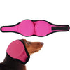 Pink noise cancelling dog ear wrap placed next to a brown dog's head.