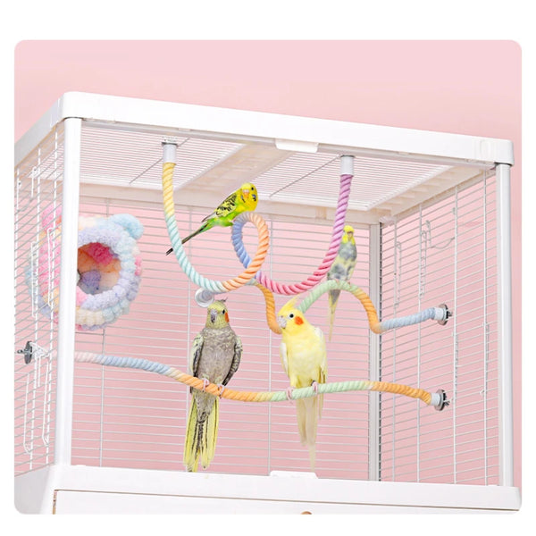 A white bird cage with colorful gradient climbing ropes and perches for birds inside.