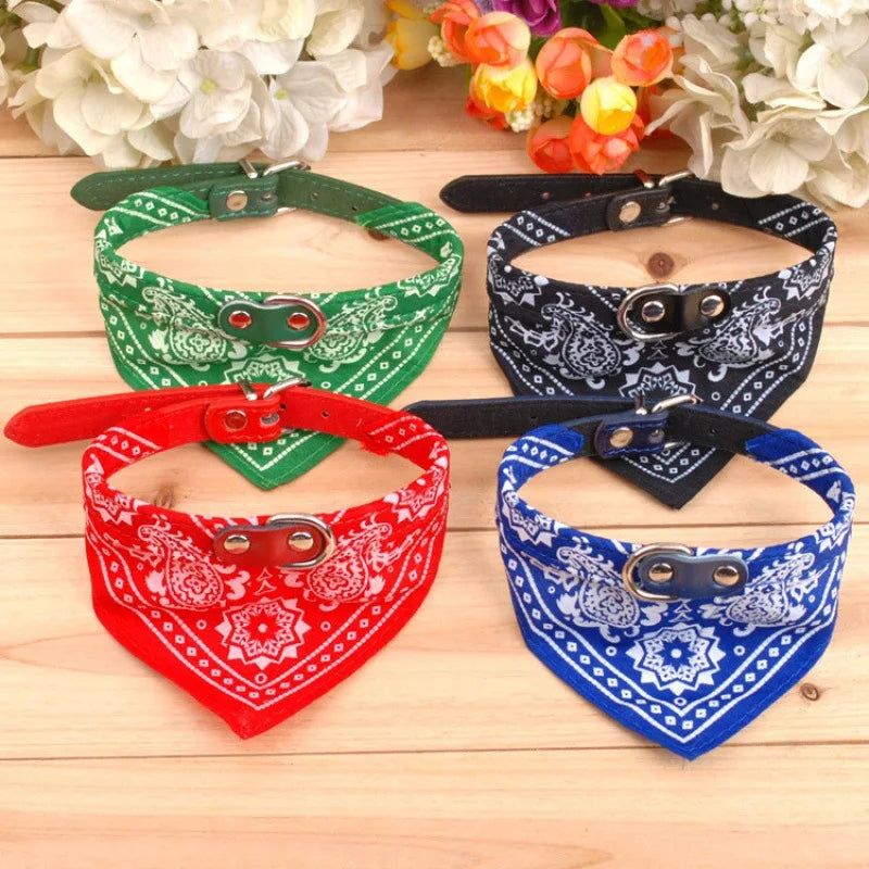 Three colorful fabric bandana collars for dogs and cats displayed on a wooden surface.