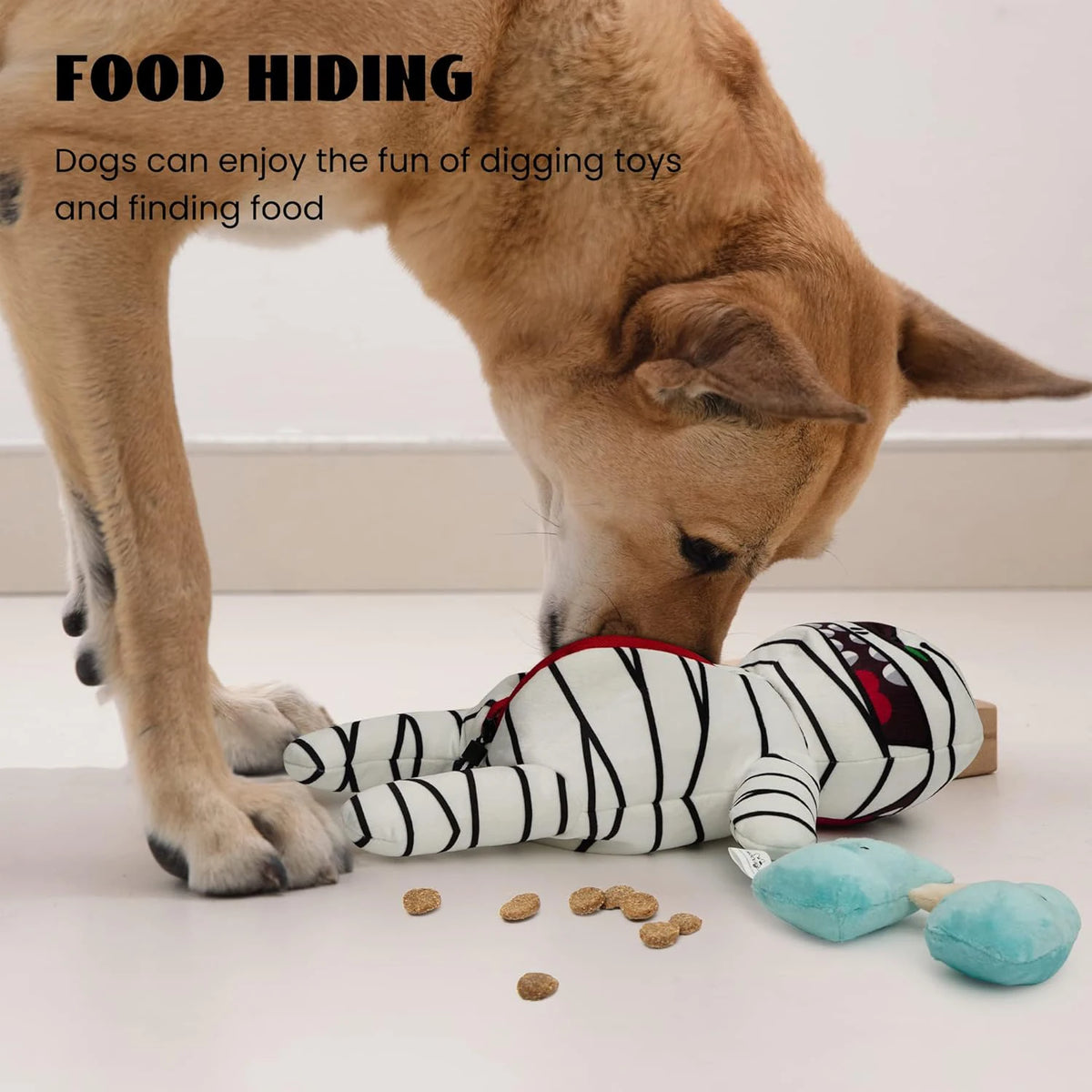 A dog is digging for food near a stuffed zombie mummy chew toy and scattered kibble.