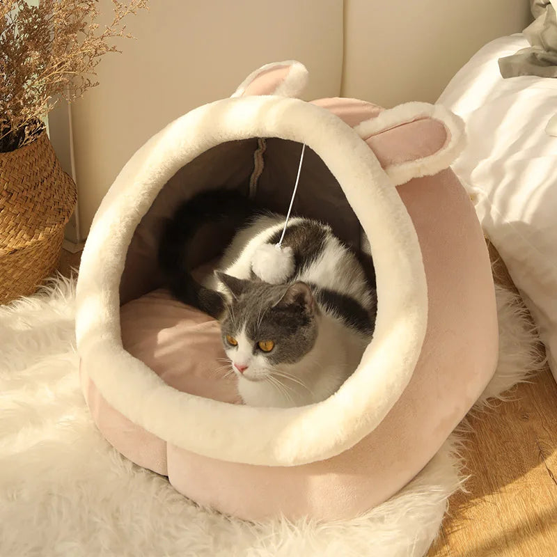 A fluffy pink pet tent bed with a round entrance is shown, containing a black and white cat.
