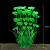 A clump of bright green artificial aquarium plants growing in sand.