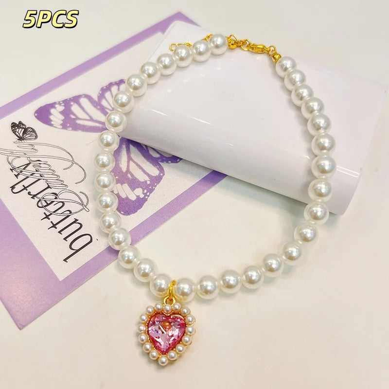 A 5 piece necklace featuring a pearl strand with a heart-shaped pink gemstone pendant.