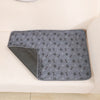 A gray reusable washable pet training mat is shown resting on a light-colored surface.