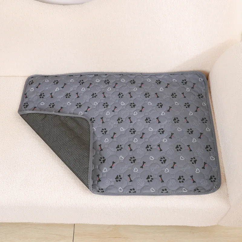 A gray reusable washable pet training mat is shown resting on a light-colored surface.