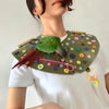 A close-up of a parrot anti-plucking and biting coat featuring green feathers and colorful buttons on a garment.