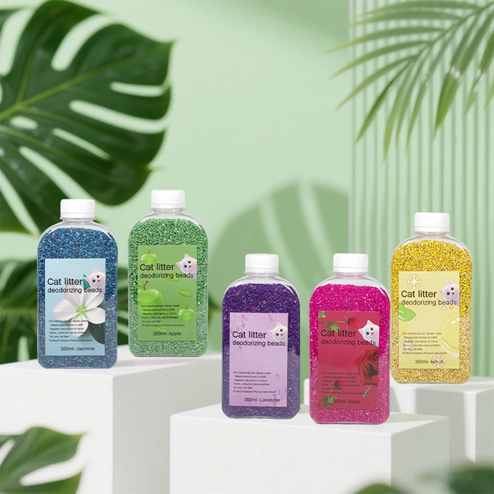 Four glass bottles of cat litter deodorizing beads in various colors like jasmine, apple, lavender, and rose are displayed on