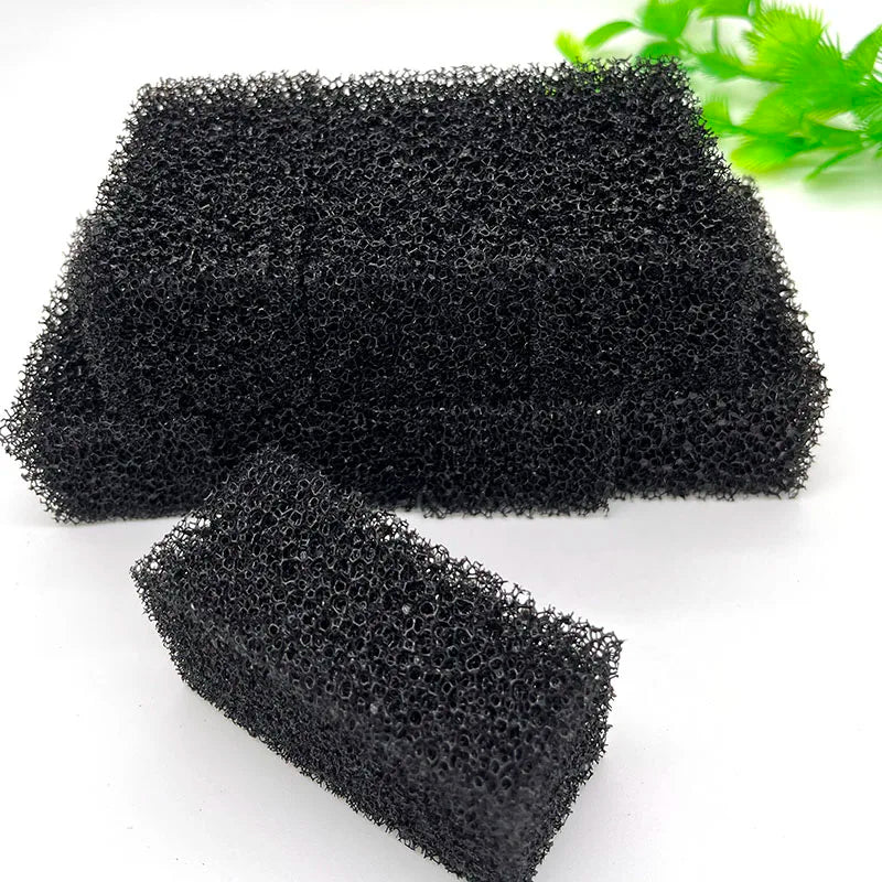 Two pieces of black aquarium bio sponge filter media are shown on a white surface.