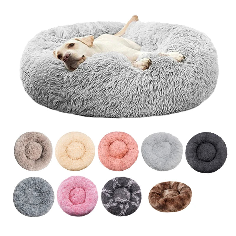 A plush round pet bed with a gray, fluffy cover, shown alongside various shades of pink, gray, and brown.