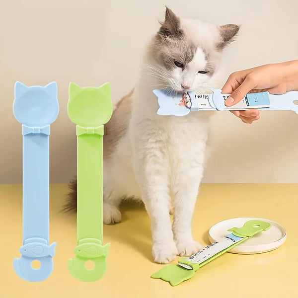 A hand is feeding a white cat with a long-handled pet food dispensing spoon, showing different colored spoons.