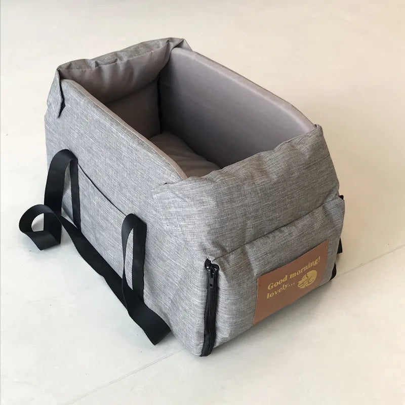 Graue, tragbare Transportbox und Autositz für Hunde und Katzen mit schwarzen Riemen und einem braunen Anhänger.