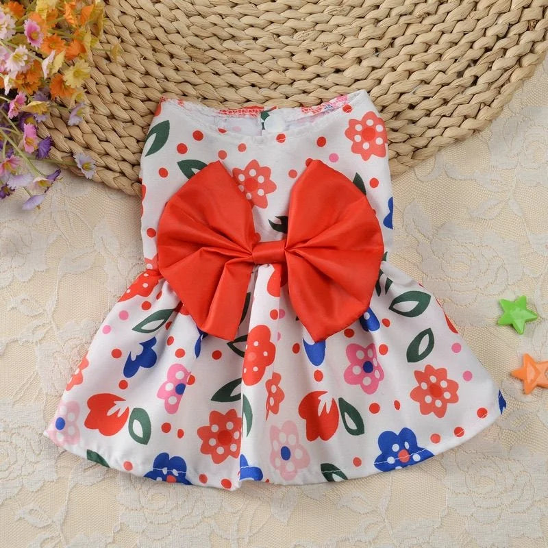 Une robe d'été blanche à imprimé floral et un nœud orange est présentée sur un tapis tissé.
