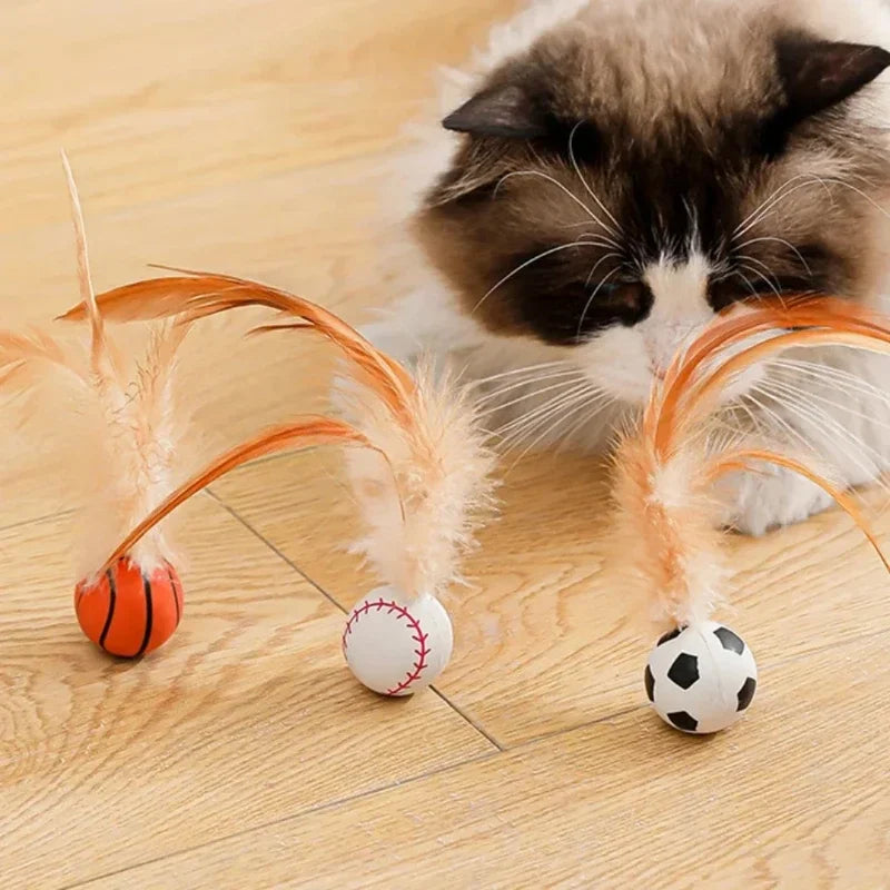 A fluffy cat is interacting with an orange and white ball decorated with feathers.