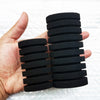 A hand holds a stack of black biological aquarium sponge filter discs.