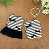 A black and white striped dog dress with a spring bow collar and flying sleeves lying on a brown surface.