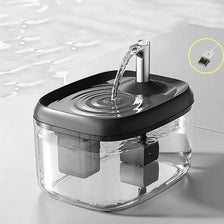 Fontaine à eau automatique en verre clair avec bec en acier inoxydable, en train de verser de l'eau.