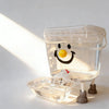 Distributeur d'eau automatique pour animaux clair avec un visage souriant, sur une surface blanche.
