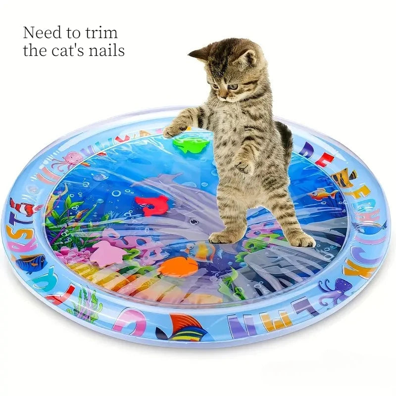 A kitten is playing with an interactive water play mat featuring an ocean fish design.