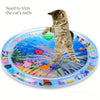 A kitten is playing with an interactive water play mat featuring an ocean fish design.