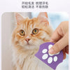 A hand is using a purple grooming comb on an orange tabby cat.