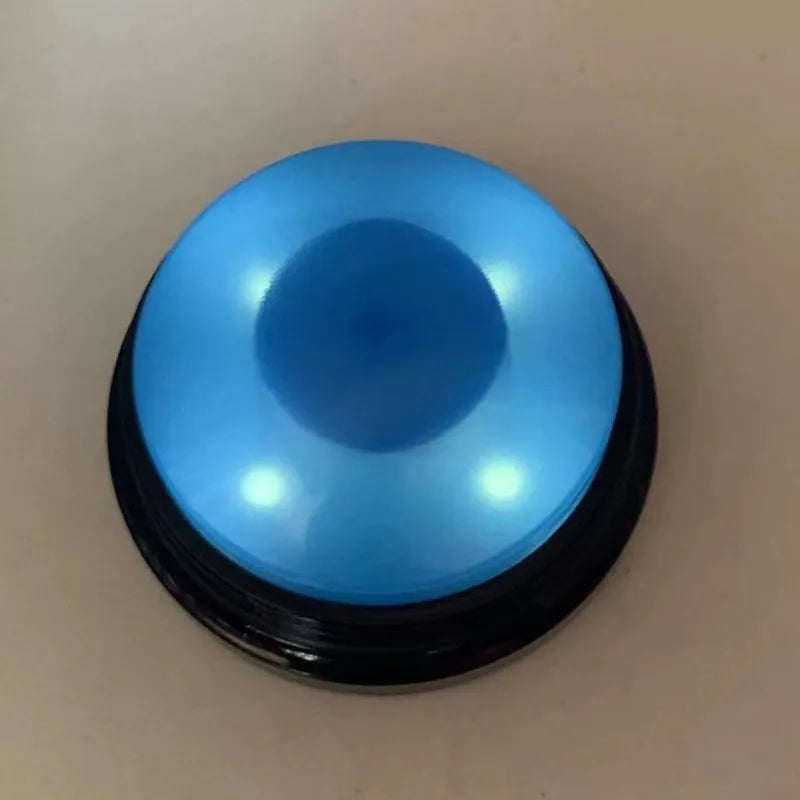 A round, light blue button with a black rim used for dog training.