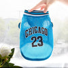 Helles blaues Hundestickjacke mit Chicago 23 Schriftzug und gestreiftem Rand wird von einer Hand gehalten.