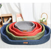 A stack of washable waterproof dog bed mats in various shades of blue, green, and orange are displayed on a white background.