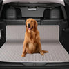 A golden retriever sits on a gray reusable pet training pad inside a car trunk.