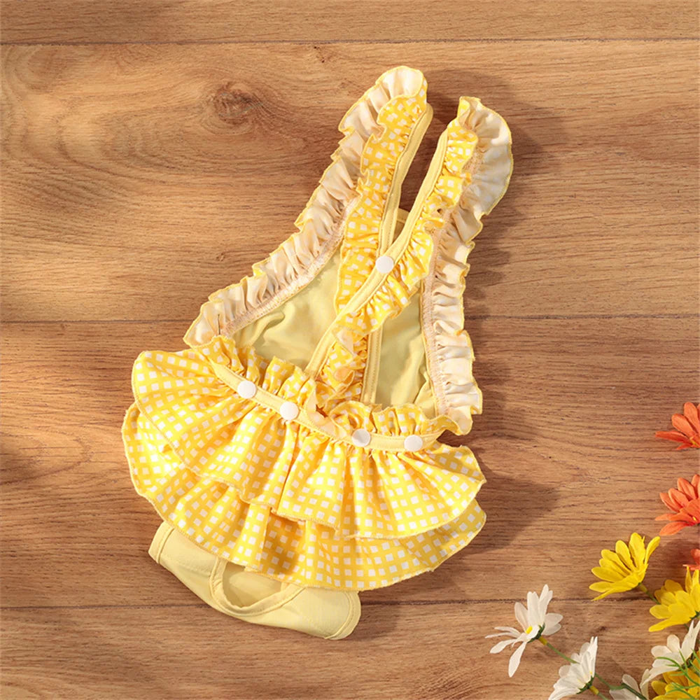 Yellow and white ruffled reusable dog diaper pants for small breeds displayed on a wooden surface.