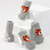 A set of four gray knit dog socks featuring an orange and black tiger print displayed on white steps.