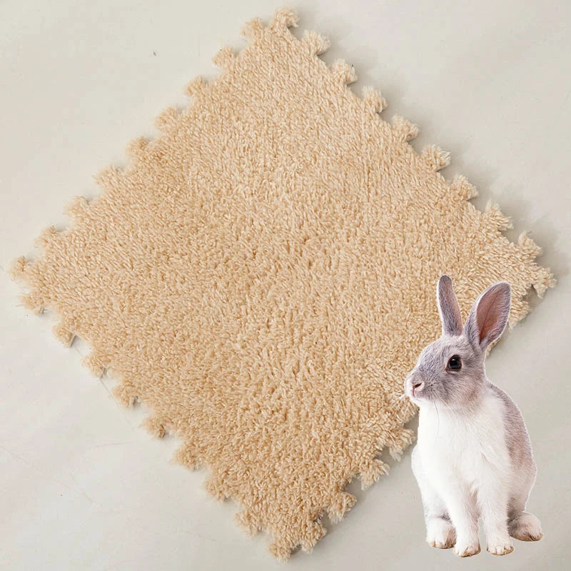 A small gray rabbit sits on a beige, fluffy fleece pet warming mat.