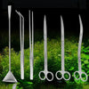 Set Edelstahl-Aquarienfreiniger mit Siphon, Pinzetten und Schere auf grünem Moos.