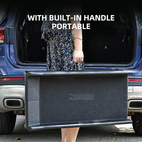 A woman holds a foldable pet ramp with a built-in handle portable on the back of a blue vehicle.