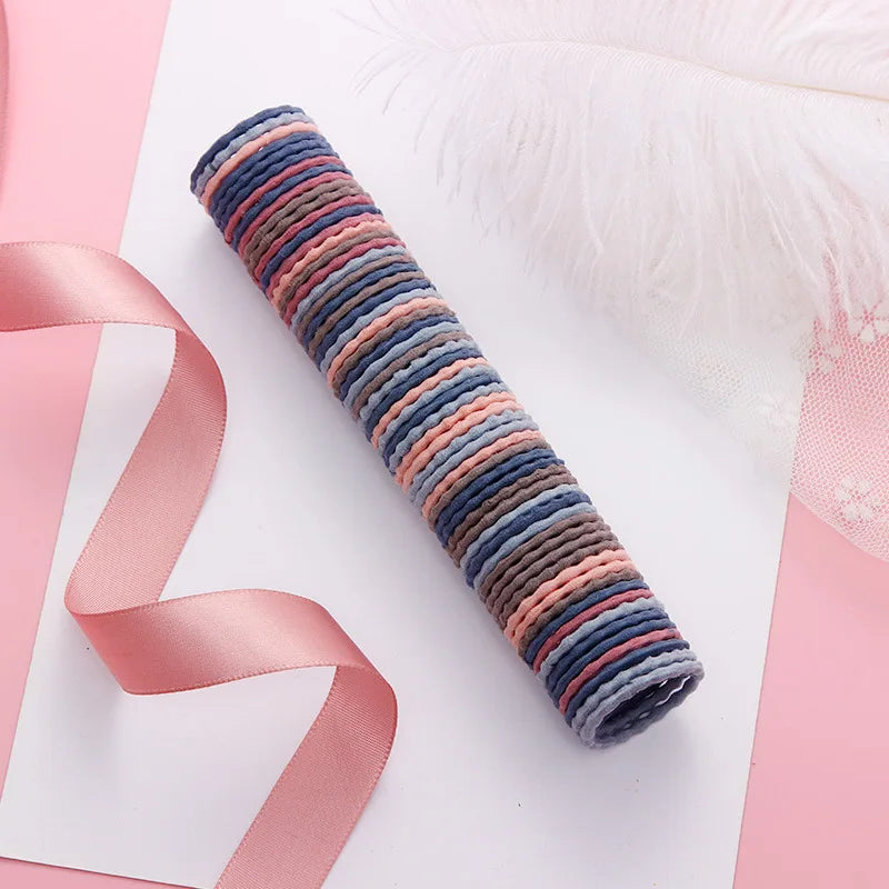 A rolled colorful elastic hair band featuring stripes of blue, pink, and gray on a white background.