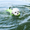 A white dog is floating on green life vest in water.