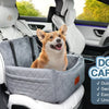 A small dog is sitting inside a gray car seat in a vehicle, demonstrating the features of a dog car seat.