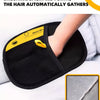 A hand is using a black grooming glove to brush hair back and forth on a pet.