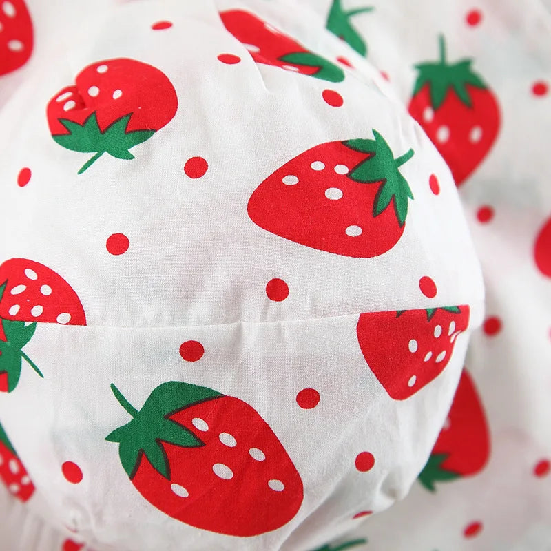 Weißes Stoffmuster mit roter Erdbeere und Polka Dots, Nahaufnahme eines Sommerkleides und Hutes.
