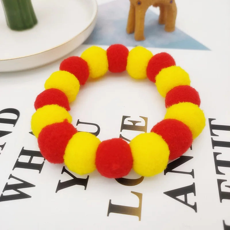 A colorful pet collar and bow tie set made of fuzzy red and yellow material lying on a white surface.
