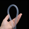 A hand is holding a clear flexible PVC tubing shaped like a loop against a black background.