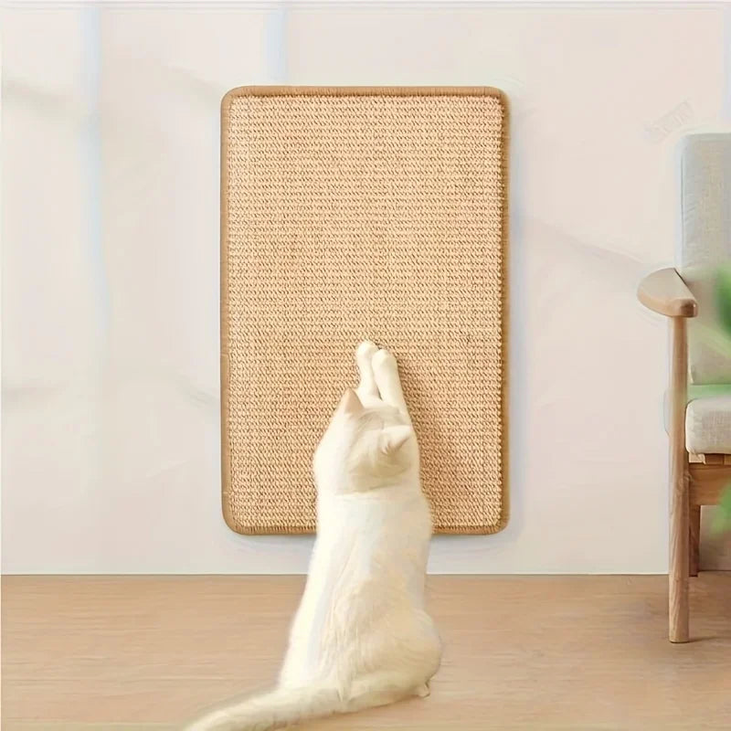 A white cat is scratching on a beige, rectangular cat scratch board mounted on a wall.