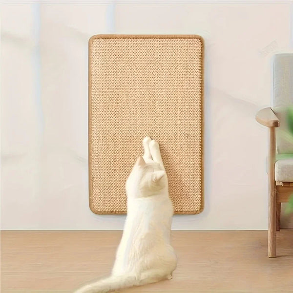 A white cat is scratching on a beige, rectangular cat scratch board mounted on a wall.