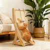 Eine orangebraune Katze entspannt sich in einem vertikalen Sisal- Kratzbaum mit Holzständer drinnen.