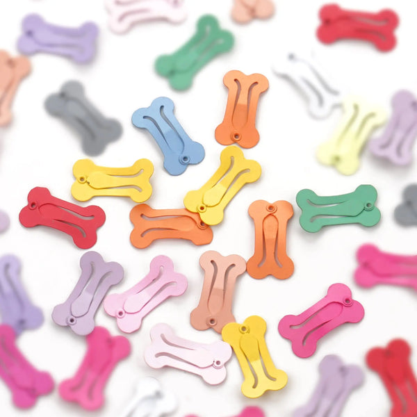 A collection of colorful dog hair clips for pet grooming scattered on a white background.