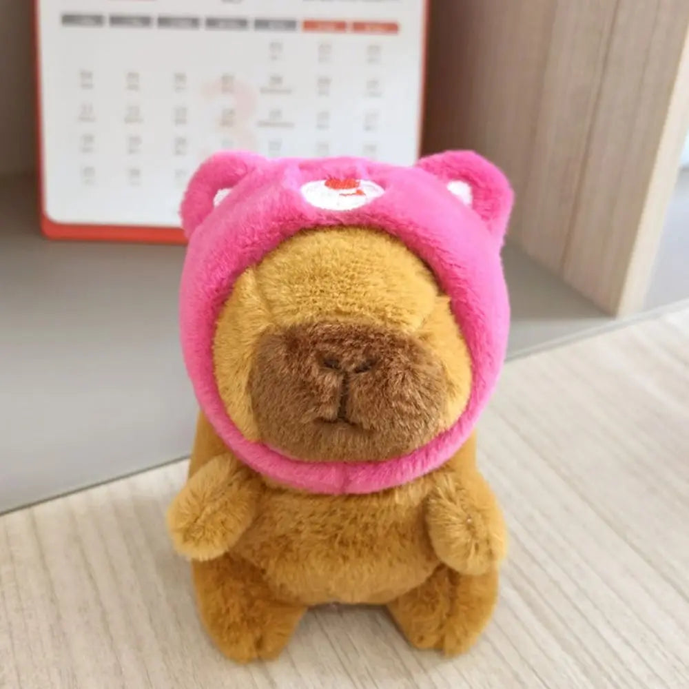 A fluffy brown capybara plush doll wearing a pink hoodie with small wings.