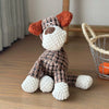 A handcrafted plush toy of a donkey with brown and white fur and orange ears sitting on a wooden surface.