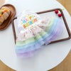 Elegant birthday suit for dogs featuring a white top and colorful tulle skirt on a wooden tray.
