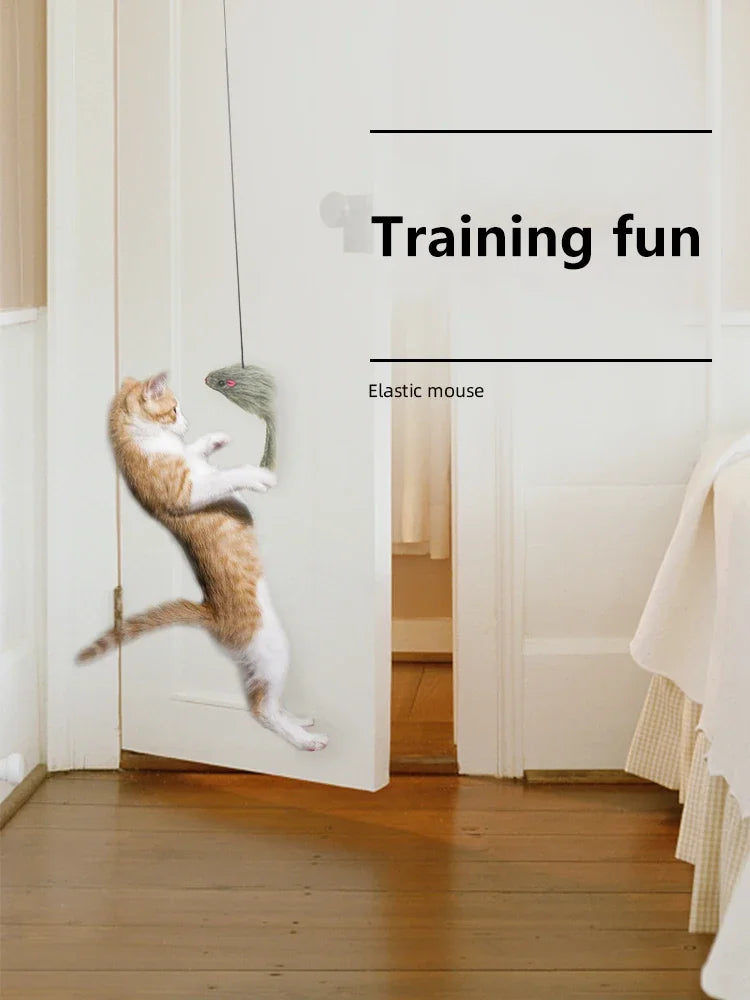 A ginger and white cat is playing with an elastic mouse toy hanging from a door frame.