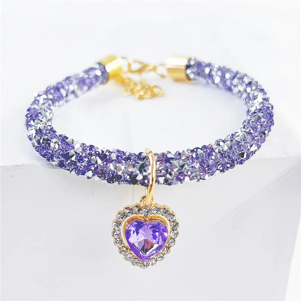 A purple crystal beaded collar with a gold clasp and a heart-shaped pendant.