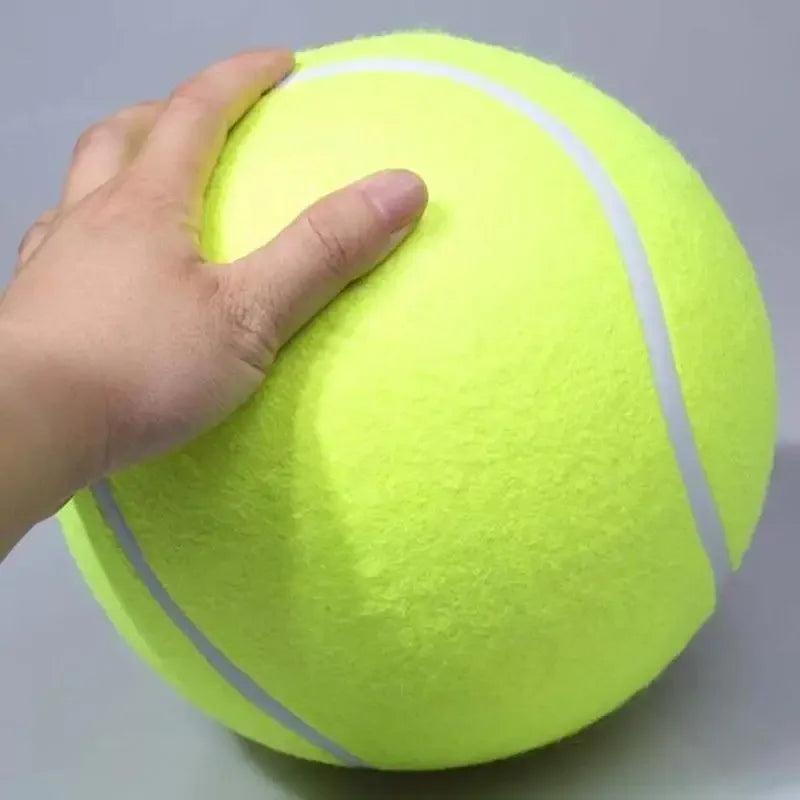 Une main serre une balle de tennis en caoutchouc jaune fluo utilisée comme jouet à mâcher pour chien.